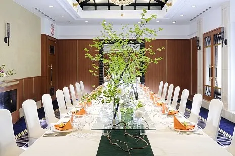 中央に1本の長いガラステーブルを配し、白いカバー付きの椅子が両脇にずらりと並ぶ、晩餐会スタイルの小宴会場。テーブル中央には新緑の鮮やかな枝物が美しく生けられた、上質でプライベート感あふれる空間です。