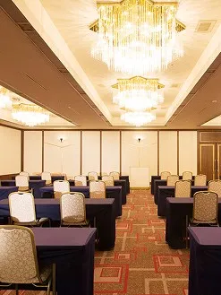 天井に豪華なシャンデリアが輝き、ビジネスセミナーや講演会用にデスクと椅子が整然と並べられた宴会場