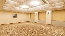 温かみのある照明に照らされ、絨毯が敷き詰められた、机や椅子のない広々としたホテルの宴会場。