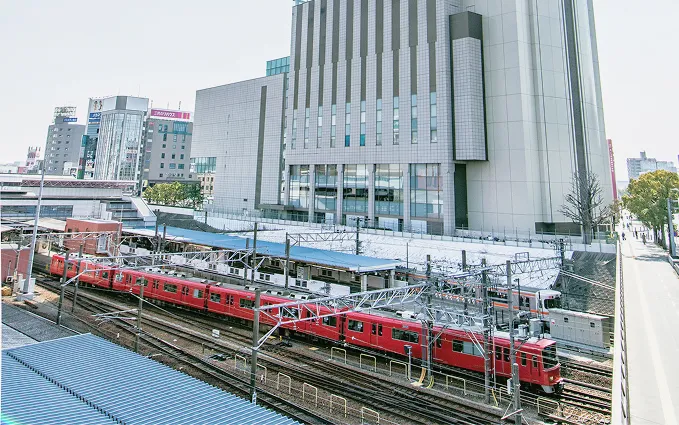 線路沿いのホームを見下ろす位置に佇む、近代的な大都市のターミナルホテル外観。