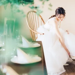 柔らかな光の中で、ウエディングドレスを身にまとい、笑顔で支度を整える花嫁。