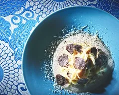 鮮やかな水色の皿に盛られた、黒トリュフを添えたクリームパスタ。