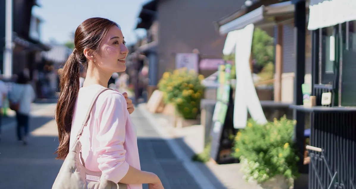 風情ある古い街並みを笑顔で散策する女性。