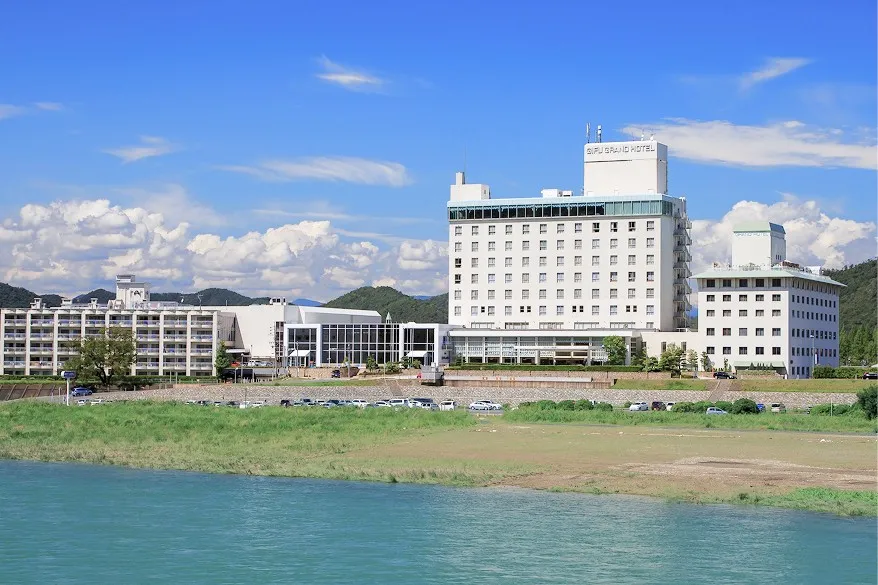 長良川の畔に佇む、青空と豊かな自然に囲まれた岐阜グランドホテルの建物外観。