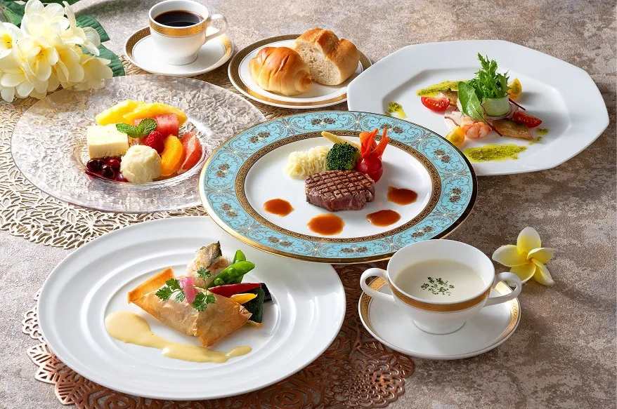 上品な洋食コース料理。中央の牛フィレステーキを中心に、スープ、前菜、魚料理、デザート、パン、コーヒーが華やかに並ぶ様子。