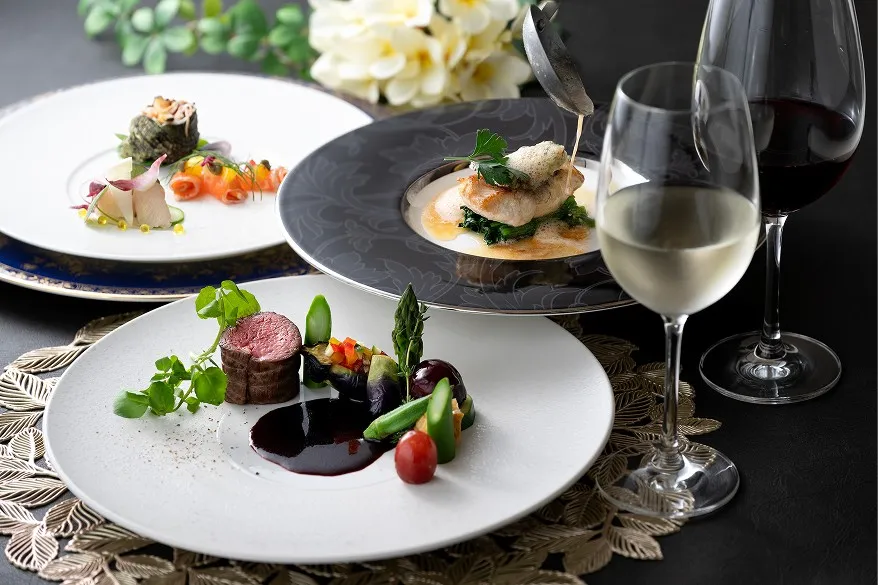 美しく盛り付けられた肉料理や魚料理のフルコースと、グラスに注がれたワイン。