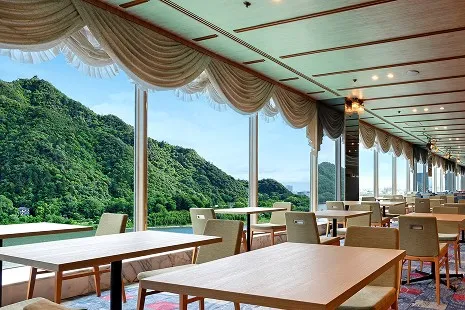 展望レストラン キャッスルの内観。大きな窓から緑豊かな山の絶景が一望できる、明るい店内の様子。