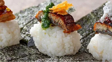 丁寧に仕立てられた創作寿司。敷かれた海苔の上に、ふっくらとしたご飯と、タレで香ばしく焼かれた鰻や色鮮やかな薬味が上品にのせられた一皿。