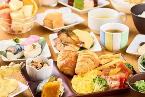 ミュッセラウンジの朝食ビュッフェ料理。クロワッサンやスクランブルエッグ、お寿司や焼き魚などがテーブルいっぱいに並ぶ様子。